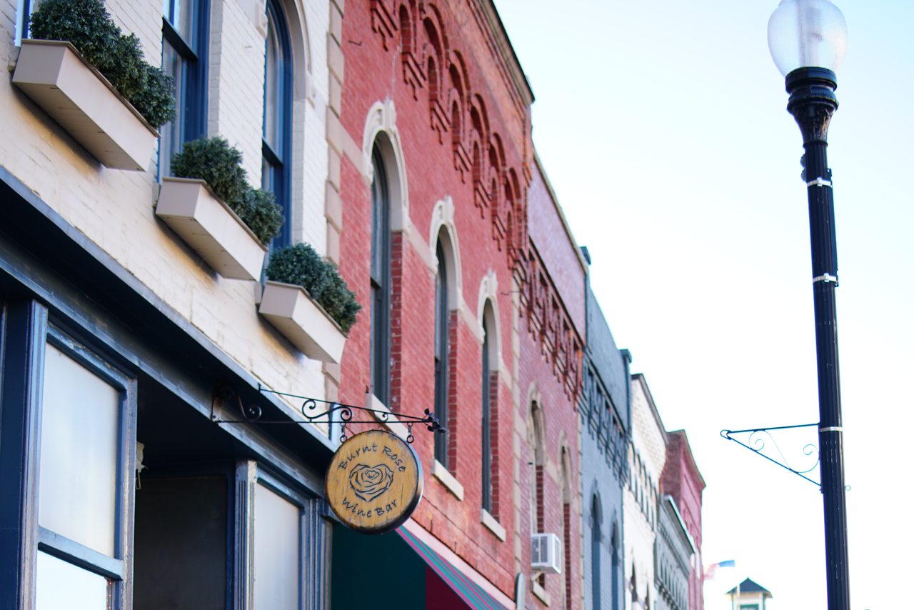Main Street in Penn Yan: brick shopfronts, a lamp post and a sign hanging over the sidewalk.